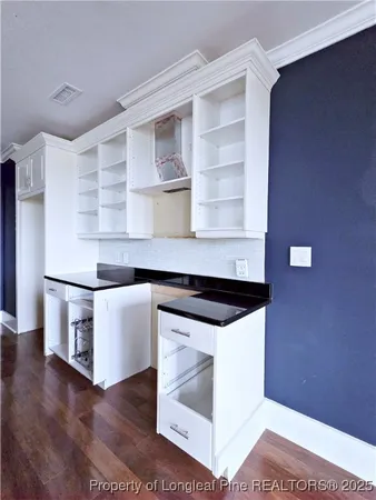a kitchen with granite countertop a stove and a white cabinets