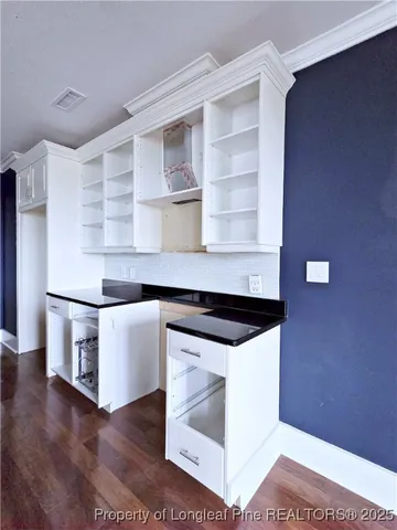 a kitchen with granite countertop a stove and a white cabinets