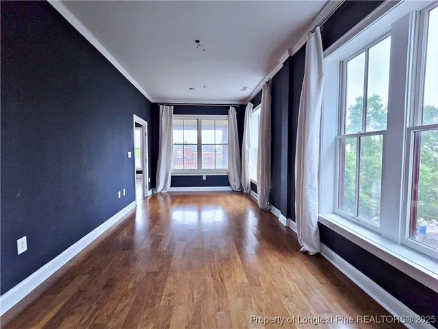 a view of an empty room with a window and wooden floor