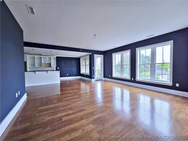 a view of an empty room with window and wooden floor