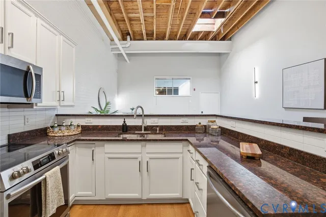 a kitchen with granite countertop a sink a stove and cabinets