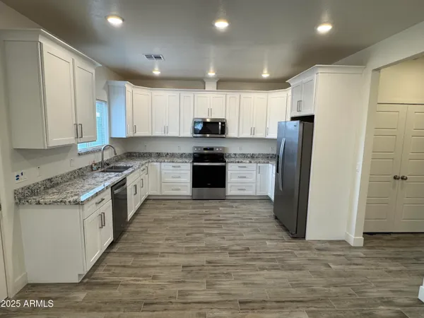 a large kitchen with stainless steel appliances granite countertop a stove top oven a refrigerator and a granite counter top