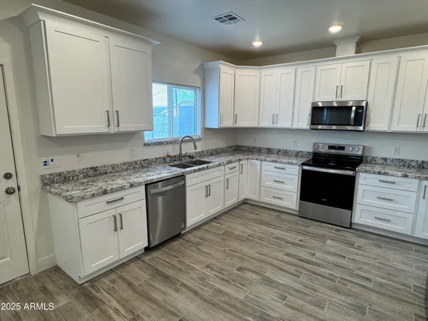 a kitchen with granite countertop white cabinets and white appliances