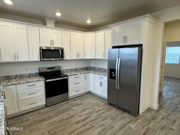 a kitchen with granite countertop white cabinets and stainless steel appliances