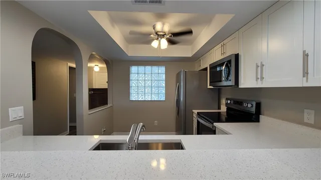 a kitchen with stainless steel appliances granite countertop a refrigerator a stove top oven a sink dishwasher and white cabinets with wooden floor