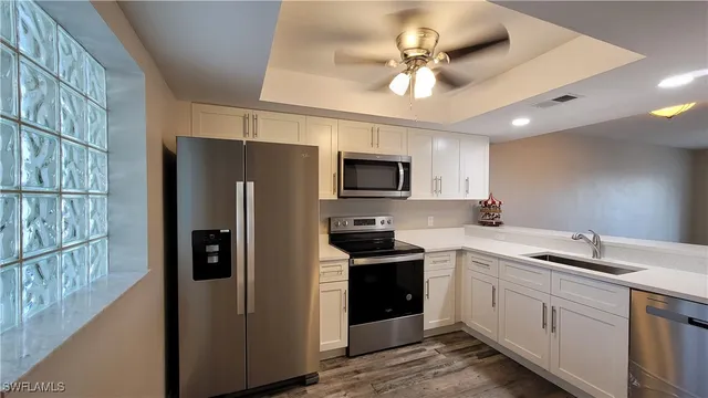 a kitchen with a sink stainless steel appliances cabinets and a window