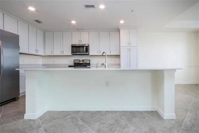 a kitchen with kitchen island sink stove and cabinets