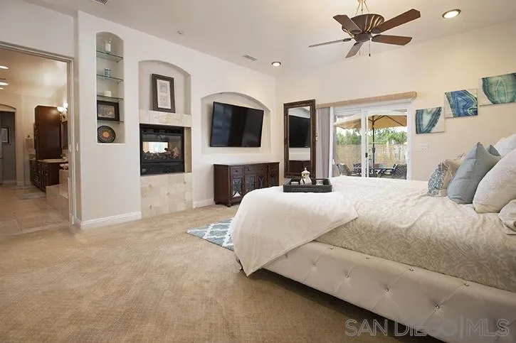 2641 Firebrand Place Alpine, CA 91901 - Photo 12 of 25 a bedroom with a large bed a flat tv screen and a fireplace