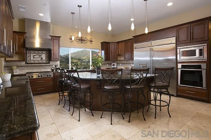2641 Firebrand Place Alpine, CA 91901 - Photo 3 of 25 a kitchen with cabinets a sink a stove a dining table and chairs