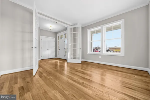 a view of an empty room with window and wooden floor