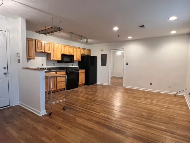 an empty room with wooden floor and stainless steel appliances