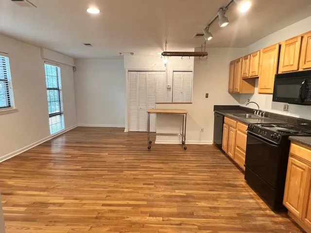 a kitchen with stainless steel appliances wooden floor and a refrigerator