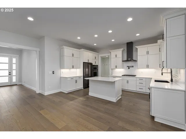a large white kitchen with kitchen island a sink a center island stainless steel appliances and a fireplace