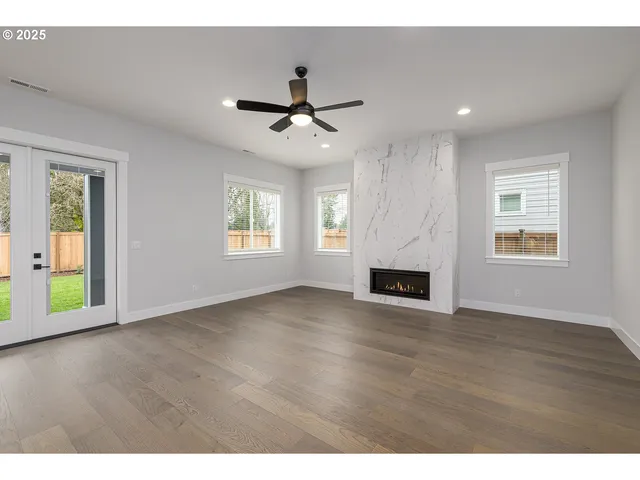 a view of a livingroom with a fireplace a ceiling fan and windows