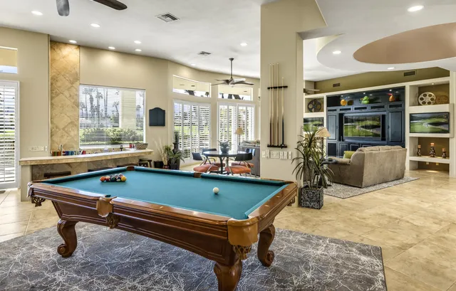 a room with furniture pool table and glass windows
