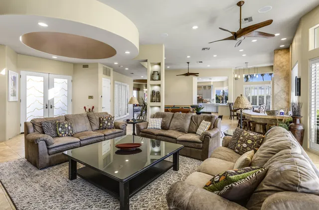 a living room with furniture kitchen view and a chandelier