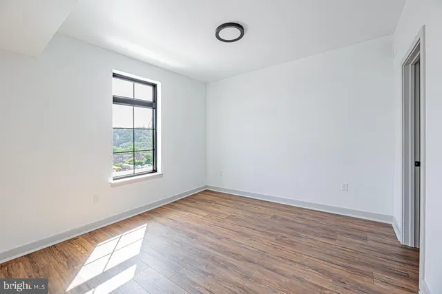 an empty room with wooden floor and windows