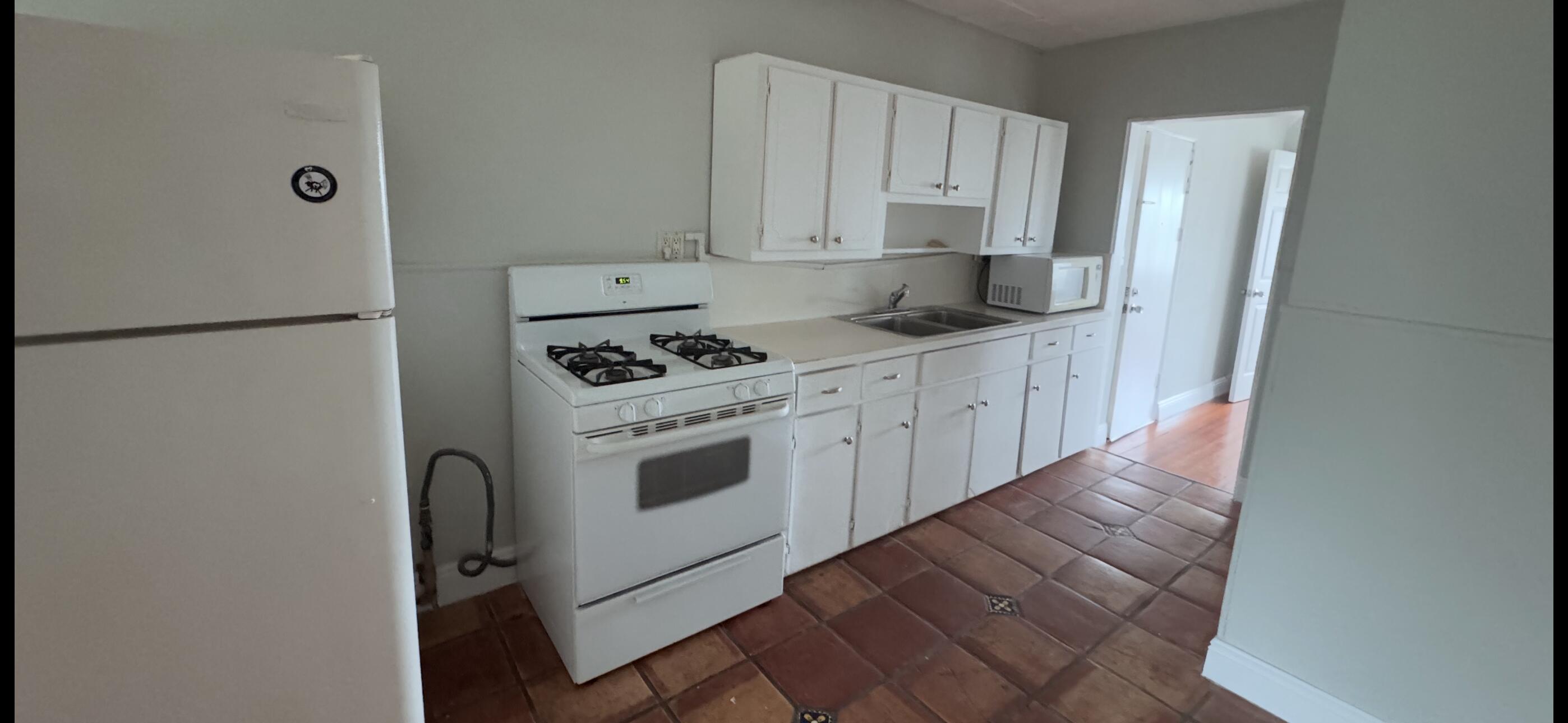 736 Omar Road, Unit 4 West Palm Beach, FL 33405 - Photo 6 of 17 a kitchen with stainless steel appliances a refrigerator sink and white cabinets