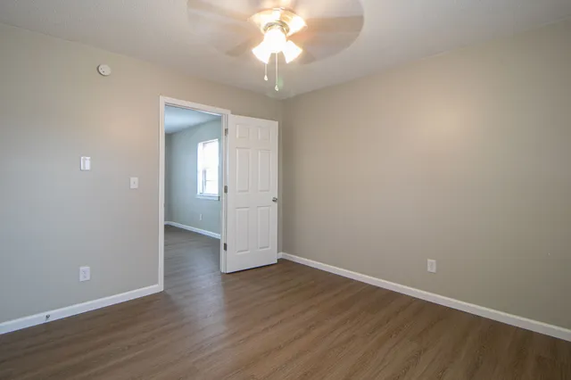 a view of an empty room with window and wooden floor