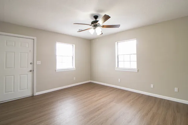 a view of an empty room with wooden floor and a window