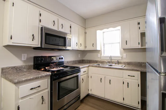 a kitchen with granite countertop white cabinets sink and stainless steel appliances