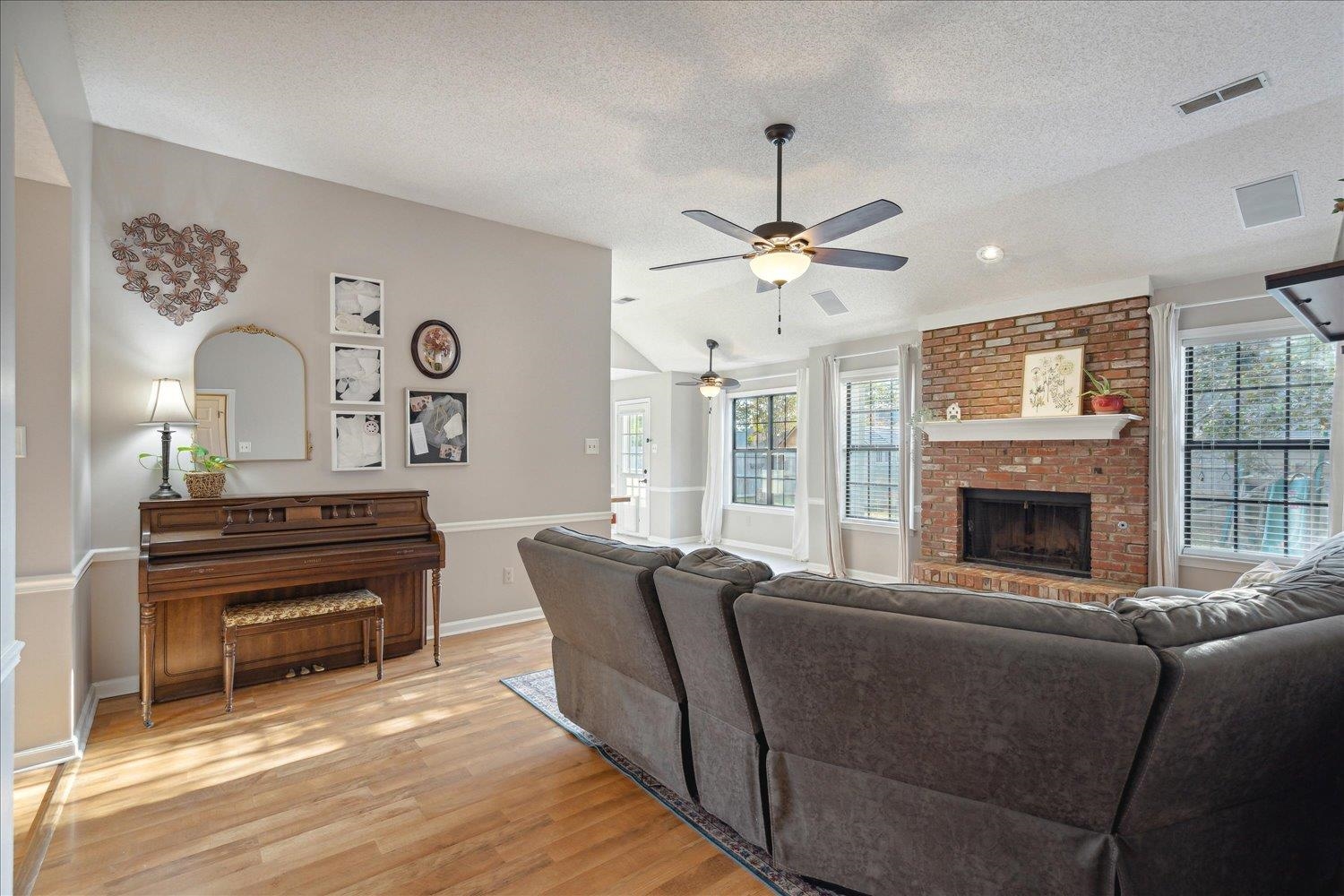 6893 Andrews Road Bartlett, TN 38135 - Photo 16 of 30 Living room with ceiling fan, a textured ceiling, light wood-type flooring, a brick fireplace, and vaulted ceiling