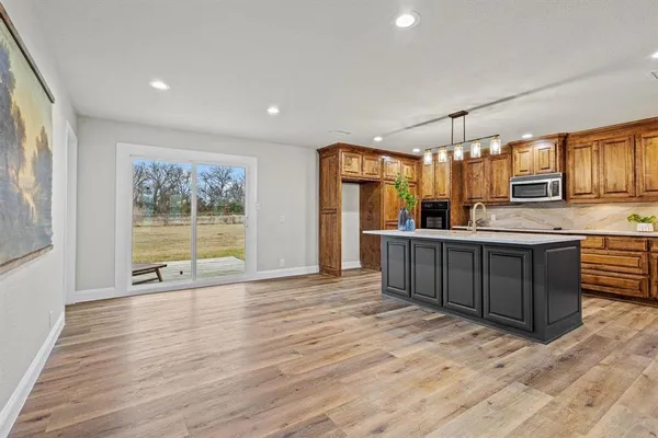 a view of kitchen with stainless steel appliances granite countertop a sink and wooden cabinets