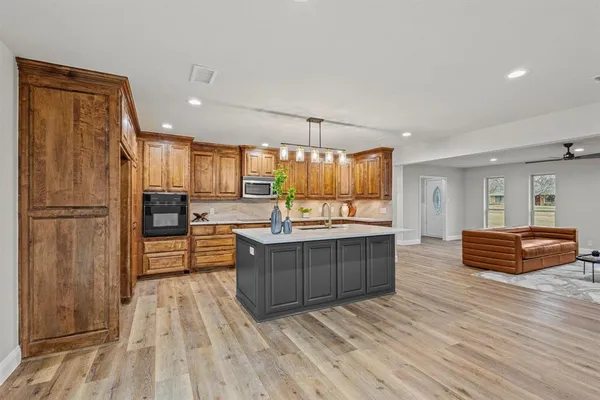 a kitchen with stainless steel appliances granite countertop a refrigerator a sink dishwasher a stove and white countertops with wooden floor