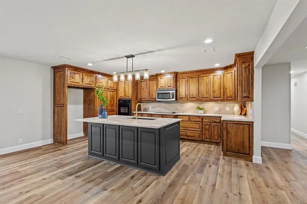 a large kitchen with a center island wooden floor stainless steel appliances and cabinets