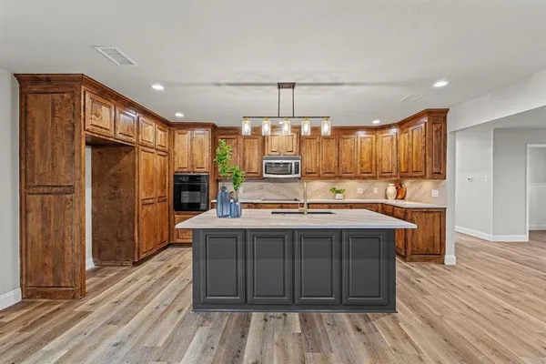 a kitchen with kitchen island granite countertop a sink refrigerator and wooden cabinets
