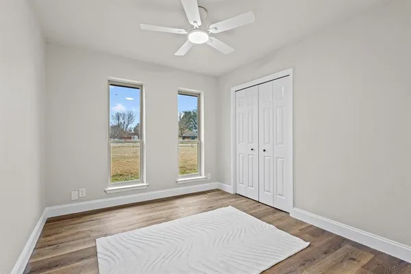 an empty room with windows and ceiling fan