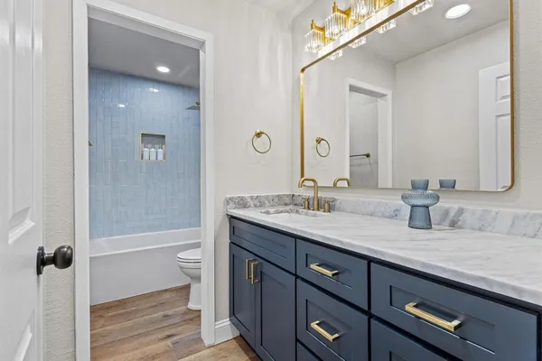 a bathroom with a granite countertop sink a toilet and shower