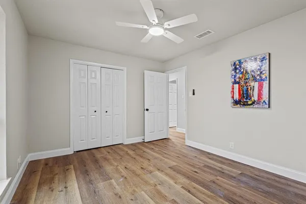 an empty room with wooden floor and ceiling fan