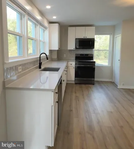 a kitchen with wooden floors a stove a microwave and a refrigerator