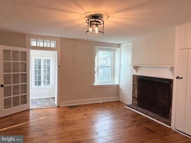 an empty room with wooden floor fireplace and windows