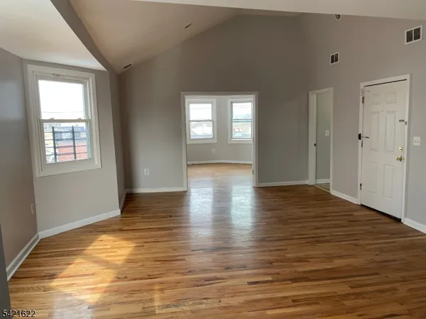a view of an empty room with window and wooden floor