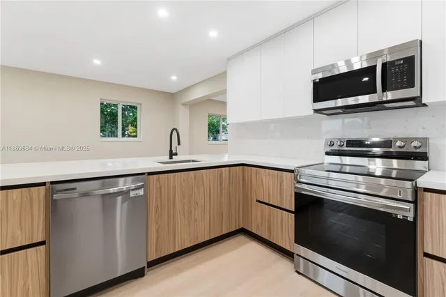 a kitchen with stainless steel appliances a sink dishwasher a microwave oven and a stove with wooden floor