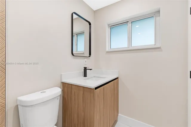 a bathroom with a granite countertop toilet sink and mirror