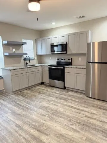 a kitchen with stainless steel appliances granite countertop a refrigerator sink stove microwave and cabinets