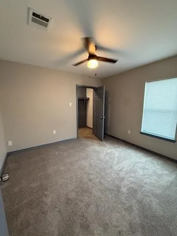 an empty room with a ceiling fan and a window