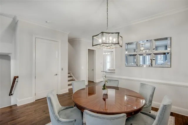 a dining room with wooden floor a chandelier a wooden table and chairs