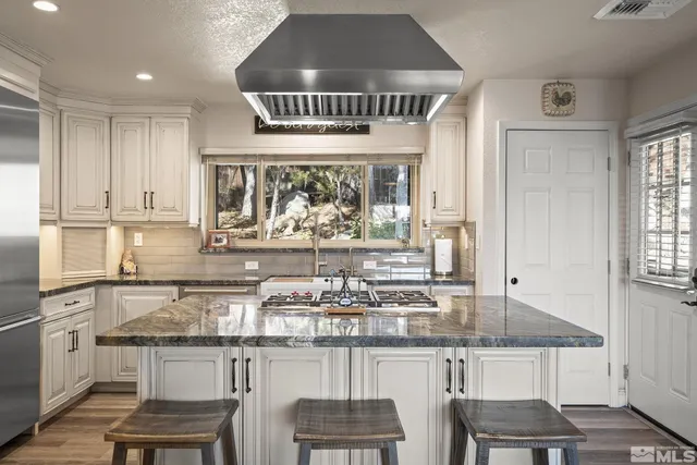 a kitchen with stainless steel appliances granite countertop a stove top oven a sink refrigerator and cabinets