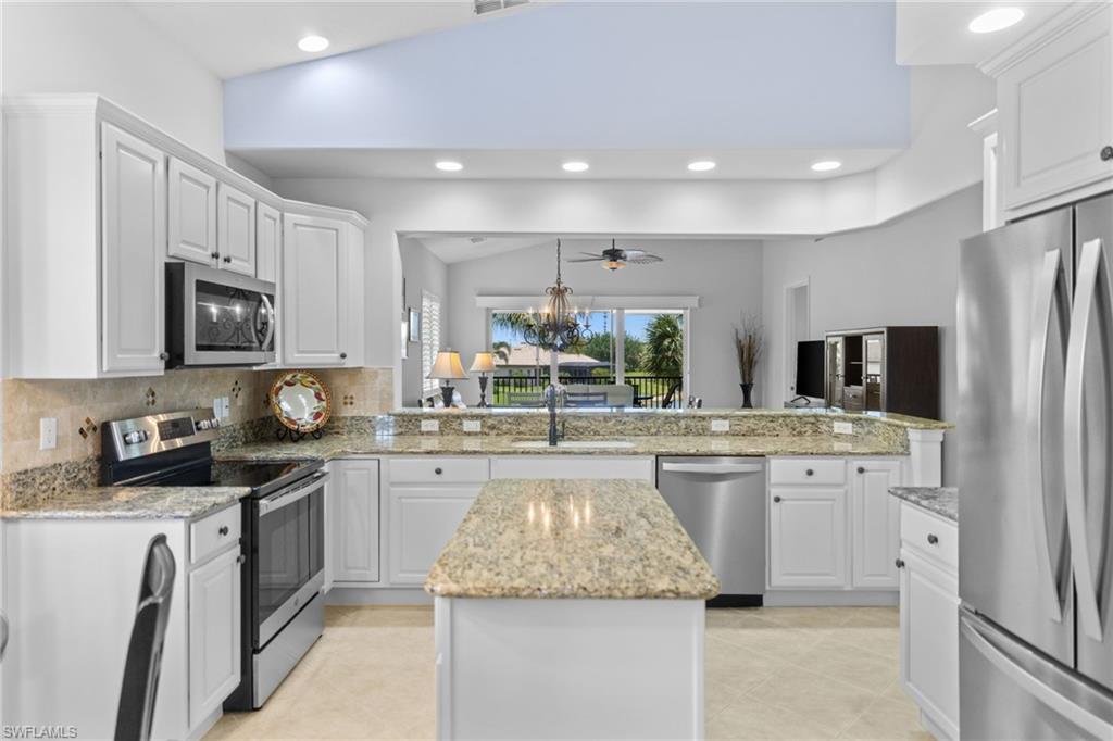 6414 Legacy Circle, Unit 903 Naples, FL 34113 - Photo 11 of 50 a kitchen with stainless steel appliances granite countertop a sink stove refrigerator and cabinets