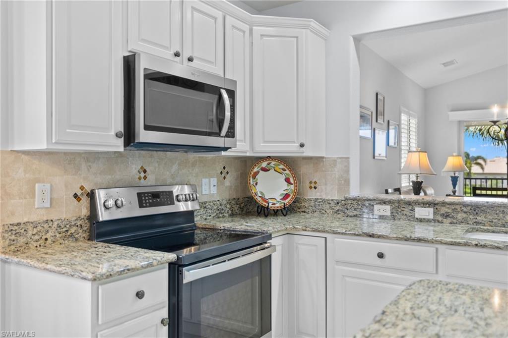 6414 Legacy Circle, Unit 903 Naples, FL 34113 - Photo 15 of 50 a kitchen with granite countertop white cabinets and white appliances