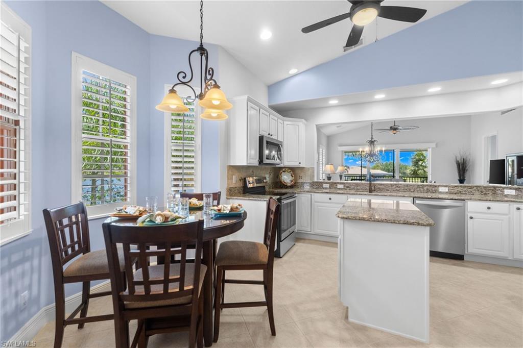 6414 Legacy Circle, Unit 903 Naples, FL 34113 - Photo 10 of 50 a kitchen with stainless steel appliances granite countertop a stove a sink dishwasher a dining table and chairs with wooden floor