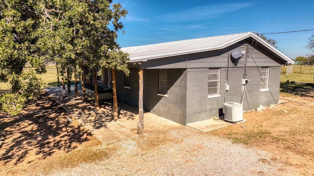1003 Lamkin Road Mineral Wells, TX 76067 - Photo 20 of 40 View of side of home with a metal roof and a central AC unit