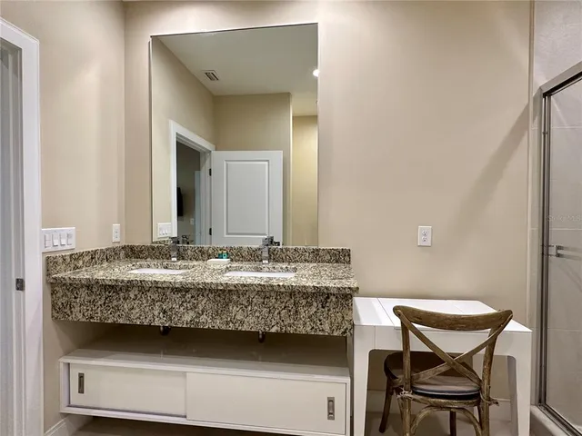 a bathroom with a granite countertop tub sink and mirror