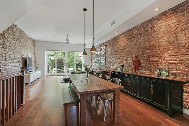 a view of a patio with couches and a table and chairs with wooden floor and fence