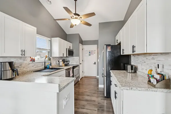 a kitchen with stainless steel appliances granite countertop a sink a stove and a refrigerator