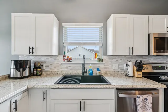 a kitchen with stainless steel appliances granite countertop a sink a stove and cabinets